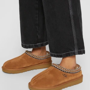 Bruna UGG mocka loafers - Säljer ett par snygga bruna loafers från UGG i mjuk mocka. De har en cool broderad kantdetalj och en bekväm sula. Perfekta för höst och vinter när du vill hålla fötterna varma och stiliga. Passar till både vardag och avslappnade tillfällen. Obs är inte hemma för tillfället så postar jag det när jag mellanlandar