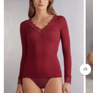 Vinröd långärmad topp med spetsdetaljer - Säljer min jättefina Intimissimi tröja i vinröd med v-ringning och spetsdetaljer vid hals och ärmslut. Perfekt för höst och vinter, den är både stilren och bekväm. Passar bra till både vardag och festliga tillfällen. Den är i nyskick, inga defekter då jag endast har använt den en gång. 