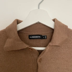 Beige stickad tröja från J.Lindeberg - Säljer en snygg beige stickad tröja från J.Lindeberg. Den har en klassisk krage och knappar framtill. Perfekt för höst och vinter, och den är i mycket bra skick. Passar både till vardags och lite finare tillfällen. Nypris 990kr, säljer den för 350kr.