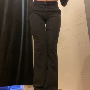 Svarta kostymbyxor - Säljer ett par stilrena svarta kostymbyxor i mycket bra skick. De är midwaist med utsvängda ben. Passar perfekt för både jobb och fest. Materialet känns bekvämt och ger en snygg siluett. Perfekta för höst och vinter! 