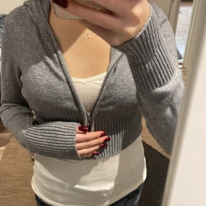 Grå hoodie med dragkedja - Säljer en supermysig grå hoodie med dragkedja. Den är croppad och har långa ärmar med ribbade muddar. Perfekt för en chill dag eller när du vill ha något bekvämt men ändå snyggt. Passar bra till jeans eller leggings! Säljer för 150 Storleken står inte men skulle säga att det är en xs,xxs