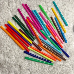 33st tuschpennor  - En samling av färgglada tuschpennor i olika nyanser som ligger utspridda på en mjuk, vit matta. Pennorna har en mängd olika färger som rosa, blå, grön, gul, orange och lila. Perfekt för att rita eller färglägga med en regnbåge av färger. Ingen penna är ritad med, mer än att jag testat alla att den verkligen fungerar. 😊