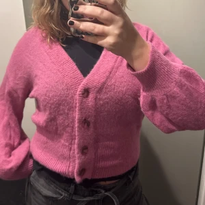 Rosa kofta från Dante 6 - Säljer en supermysig rosa kofta från Dante 6 i storlek XL. Den är gjord av en mjuk blandning av alpacka, ull och polyamid. Koftan har en v-ringad design med knappar framtill och långa ärmar. Perfekt för höst och vinter! 💖