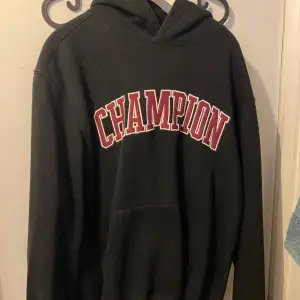 Säljer en svart hoodie från Champion i bra skick. Den har en stor, röd logga på framsidan och en klassisk känguruficka. Perfekt för höst och vinter, och passar både till vardags och träning. Storleken är normal och den är superbekväm att ha på sig. Nypris 1500