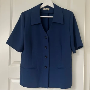 Blå kavaj med kortärmad design - Snygg blå kavaj från Valerie Stevens i ett klassiskt snitt. Den har korta ärmar och knäpps med knappar framtill. 