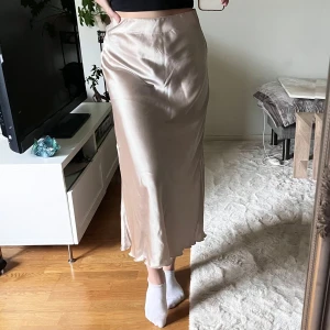 Finkjol  - Glansig kjol i storlek S, från Lager157. Resår i midjan och dragkedja på sidan. Nyskick.