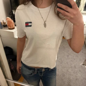 Tommy Hilfiger - En vit Tommy Hilfiger T-shirt, aningen kortare, i storlek XS. Passar perfekt till sommaren då den är luftig. Passar med jeans såsom kjol och shorts. Skriv vid frågor! 💗🤗
