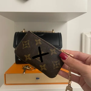 Brun och guld plånbok - Säljer en snygg liten plånbok/key pouch. Den har en dragkedja upptill och en kedja som gör den lätt att fästa i väskan/nyckelring/jeans. Perfekt för att hålla ordning på kort och småsaker. Passar både till vardag och fest!