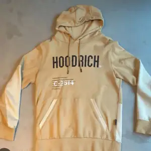 Säljer en snygg beige hoodie från Hoodrich i bra skick. Den har en stor ficka fram och justerbar huva med snören. Säljer då jag ej använder den längre. Utmärkt skicka storlek M 