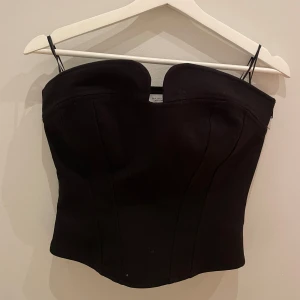 Svart korsett från Zara - Snygg svart korsett från Zara i storlek S. Den har en elegant och stilren design och en formad passform. Perfekt för festliga tillfällen eller en utekväll. Tillverkad i ett bekvämt material som sitter bra på kroppen. Nypris 330kr