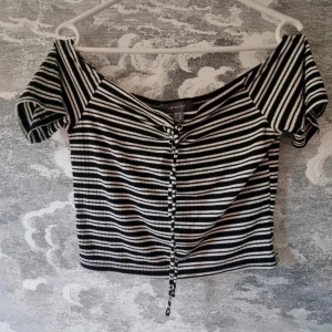 Randig offshoulder topp - Snygg svartvit randig offshoulder topp från primark. Snörning framtill och är gjord i en mjuk blandning av polyester, viskos och elastan.