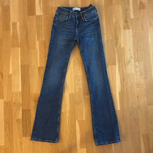 Blå jeans från Zara - Säljer ett par snygga blå jeans från Zara i storlek EUR 32. De är högmidjade och har en bootcut-stil som ger en trendig look. Perfekta för både vardag och fest! 🥳