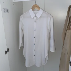 Vit skjorta från Philosophy - Snygg vit skjorta från Philosophy med knappar framtill. Skjortan har en klassisk krage och trekvartsärmar, perfekt för en stilren look. Den är tillverkad i ett lätt och bekvämt material.