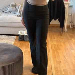 Svarta kostymbyxor - Snygga svarta kostymbyxor med hög midja och rak passform. Perfekta för en stilren look. Byxorna har en klassisk design som passar till många olika tillfällen.