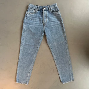 Blå jeans från Never Denim - Mom jeans från Never Denim  med hög midja och knappgylf. Perfekta i längden, är 158 cm. Använda endast fåtal gånger, så de är som nya! 