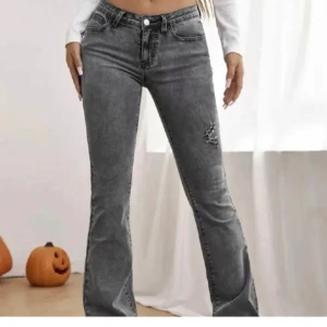 Grå bootcut jeans - Snygga grå bootcut jeans med låg midja och slitna detaljer. Perfekta för en trendig look. De har en klassisk femficksdesign och knappar framtill.