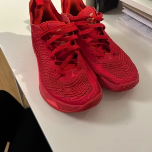 Jordan Luka 1 basketskor - Snygga röda sneakers med snörning och en sportig design. Skorna har en stilren look med detaljer i guld på plösen. Perfekta för en casual stil med en touch av färg. Basketskor.