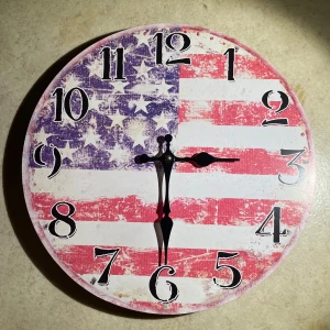 Väggklocka  - Snygg rund väggklocka med motiv av den amerikanska flaggan i rött, vitt och blått. 