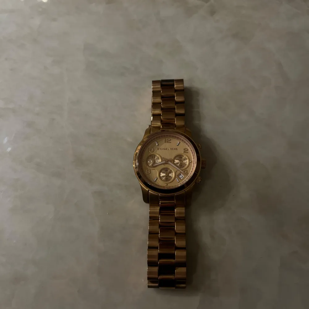 Snygg guldfärgad klocka från Michael Kors med metallarmband och flera urtavlor. Perfekt accessoar för att lyfta din stil. Klassisk design med en modern touch.. Asusteet.