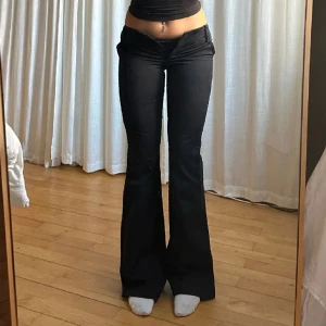 Bruna bootcut kosymbyxor - Snygga bruna bootcut kostymbyxor med låg midja. Perfekta för en trendig look med en tight passform upptill och utsvängda ben. Byxorna har knappar bak och är gjorda i ett mjukt material.