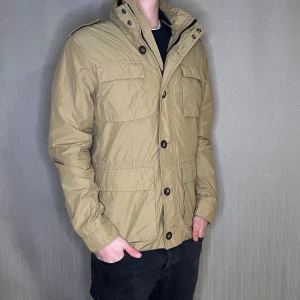 Field jacka i storlek M  - Fieldjacka från East West 🤍🌟 Storlek: M Färg: Beige 🏜️ Skick: Som ny – inga tecken på användning! Modellen på bilden är 183 cm och väger 75 kg.