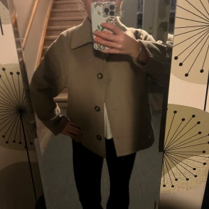 Kappa  - Snygg beige kappa med knappar framtill. Jackan har en klassisk krage och långa ärmar, perfekt för höst och vår. Enkel och stilren design som passar till många olika outfits. Från monki i storlek M för att få lite oversized (har S i vanliga fall) 