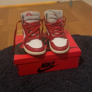 Nike air Jordan 1 red retro high limited edition (nästan aldrig använda) - Snygga Nike Air sneakers i rött och vitt med klassisk design. Skorna har snörning och en hög krage för extra stöd. Perfekta för dig som vill ha en stilren och sportig look.