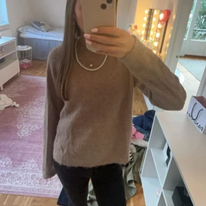 Brun stickad tröja från Zara  - Säljer en mysig beige stickad tröja med långa ärmar. Perfekt för kyliga dagar och lätt att matcha med olika outfits. Tröjan har en enkel och stilren design.