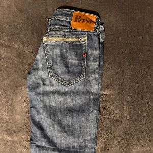 Blå jeans från Replay - Snygga blå jeans från Replay med klassisk femficksdesign och en läderpatch med logga på baksidan. Jeansen har en normal passform och är tillverkade i slitstarkt denim. Perfekta för en avslappnad stil. Storlek W30 L32