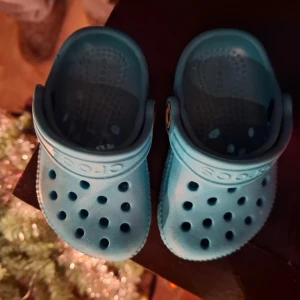 Blå / blågröna Crocs sandaler baby  - Säljer ett par blågröna Crocs sandaler för baby eller ett litet barn med små fötter 😅 helt nya! Klassisk design och ventilationshål. Perfekta för sommarens äventyr och enkla att rengöra. De har en justerbar hälrem för bättre passform. 