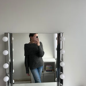 Grå stickad tröja - Säljer en mysig grå stickad tröja med en unik offshoulder-design. Perfekt för kyliga dagar och ger en stilren look. Tröjan har långa ärmar och en ribbad kant vid ärmslut och nederkant.