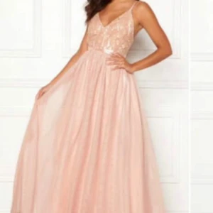 Rosa balklänning  - Elegant ljusrosa långklänning med spetsdetaljer och öppen rygg. Klänningen har smala axelband och en v-ringad urringning. Perfekt för speciella tillfällen. Denna klänning är endast använd 1 gång och bedöms därav i mycket fint skick.