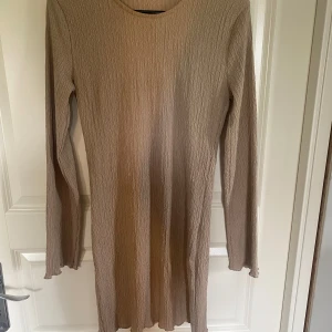 Klänning  - Beiga kortare kläning med lite mönstring. Går lite över knäna och är enbart använd en gång 