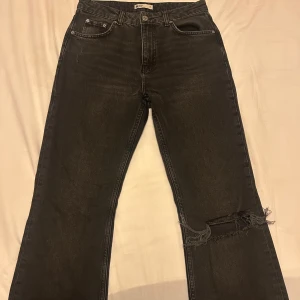 Jens från Gina Tricot  - Säljer ett par mörkgråa bootcut jeans från Gina Tricot med slitningar i storlek 38. De är använda ett fåtal gånger och är i gott skick.