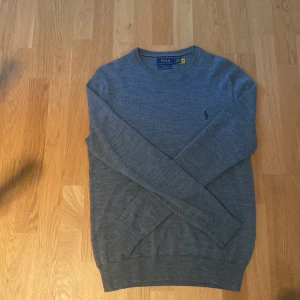 Ralph lauren stickad tröja - En riktigt snygg grå Ralph lauren tröja i merino ull. Köpt på NK, har använt den va 5 gånger och den är i riktigt bra skick. Skriv för mer frågor!