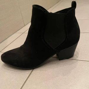 Svarta stövletter i mocka - Säljer ett par snygga svarta stövletter i mocka. De har en spetsig tå och en liten klack som ger en elegant touch. Perfekta för höst och vinter, och funkar lika bra till vardags som till fest. De är i bra skick och redo för en ny ägare!
