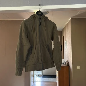 C.P. COMPANY ZIP HOODIE - Grön C.P. Company zip hoodie i storlek M Den har en liten klorin fläck på ryggen men annars bra skick