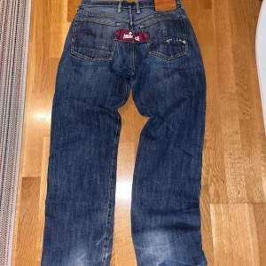 Ett par äldre evisu jeans med tag  Tagen saknar en knapp, påverkar inte hur jeansen ser ut så mycket men går att fixa 