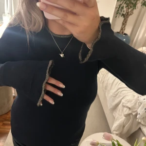 Finstickad tröja med gulddetaljer - Säljer denna superfina marinblå tröjan med gulddetaljer vid halsen och rund ärmarna. Den är även lite utsvängd vid händerna. Använd några få gånger.