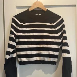 Randig croppad tröja från COS - Säljer en superfin randig tröja från COS i svart och vit. Den är croppad och har långa ärmar, perfekt för en stilren look. Materialet är en blandning av viskos, polyamid och elastan vilket gör den både bekväm och stretchig. Passar perfekt till både vardag och fest!