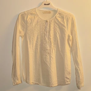 Vit långärmad blus från Zara Girls - Säljer en söt vit långärmad blus från Zara Girls. Blusen har fina detaljer med små knappar framtill och ett diskret mönster i tyget. Perfekt för både vardag och festliga tillfällen. Superbekväm och lätt att matcha med olika outfits!