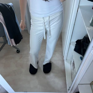 Vita mjukisbyxor med snörning - Säljer ett par superbekväma vita mjukisbyxor. De har en loose passform och är perfekta för en chill dag hemma eller en avslappnad promenad. Byxorna har snörning i midjan för justerbar passform.