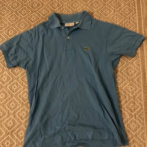 Blå pikétröja från Lacoste - Blå pikétröja från Lacoste i storlek S. Skriv om du undrar något. Mvh Simon