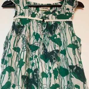 Grön och vit ärmlös klänning från Nümph - Säljer en söt kortärmad klänning från Nümph med grönt och vitt mönster av fjärilar och blommor. Den är i gott skick, ta kontakt för att veta mått osv🥰