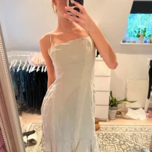 Ljusgrön klänning från Gina Tricot - Säljer en stilren ljusgrön klänning från Gina Tricot med smala axelband och en volangdetalj vid fållen. Perfekt för sommarens varma dagar. Klänningen har en enkel och elegant design som passar till många tillfällen.