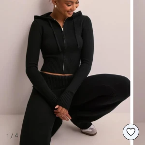 Svart ribbat mjukis sett - Snygg svart croppad hoodie med dragkedja och ribbade detaljer & matchande byxor. Perfekt för en avslappnad stil med långa ärmar och en bekväm passform.