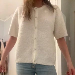 Kofta med knappar - Säljer en söt vit kofta med korta ärmar och pärlknappar framtill. Perfekt för en stilren och mysig look och endast använd en gång ✨