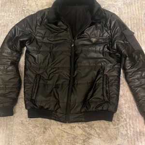 Prada Jacka Svart - Säljer min snygga Prada jacka med päls, eftersom behöver inte den längre. Har använt den  kanske 5-7 ggr. Jag är 183 passar mig perfekt, inga skador, håller dig varmt. För mer frågor d ba skriva.