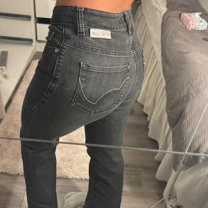 Svarta jeans med strassdetaljer - Snygga svarta jeans med hög midja och raka ben. De har coola strassdetaljer på bakfickorna som ger en extra touch. Perfekta för att lyfta din outfit! Storlek 36/32 från MAC