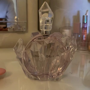 Parfym från Ariana Grande - En elegant parfymflaska från Ariana Grande med en unik kristallformad design. Flaskan är rund och har en ljuslila nyans som ger ett lyxigt intryck. Perfekt för den som älskar stilfulla och iögonfallande parfymer. Pris kan diskuteras vid snabb affär 